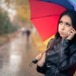Autumn Girl in Black Leather Jacket Holding a Rainbow Umbrella and a Smartphone