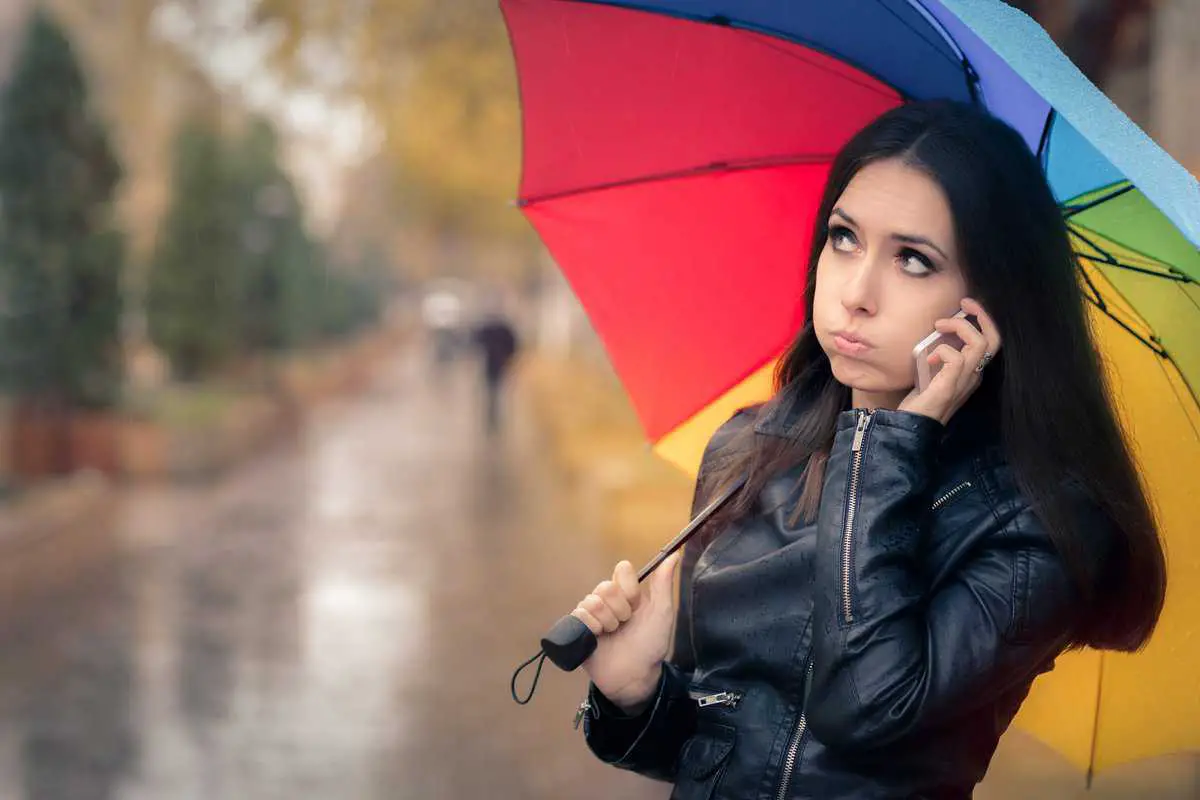 Autumn Girl in Black Leather Jacket Holding a Rainbow Umbrella and a Smartphone