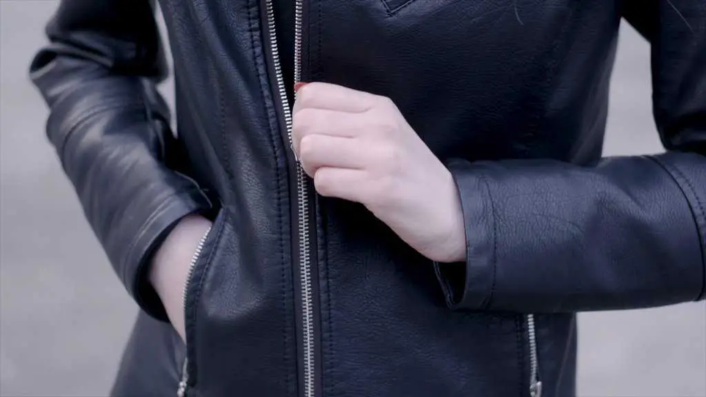 Woman wearing trendy black leather jacket with zipper.