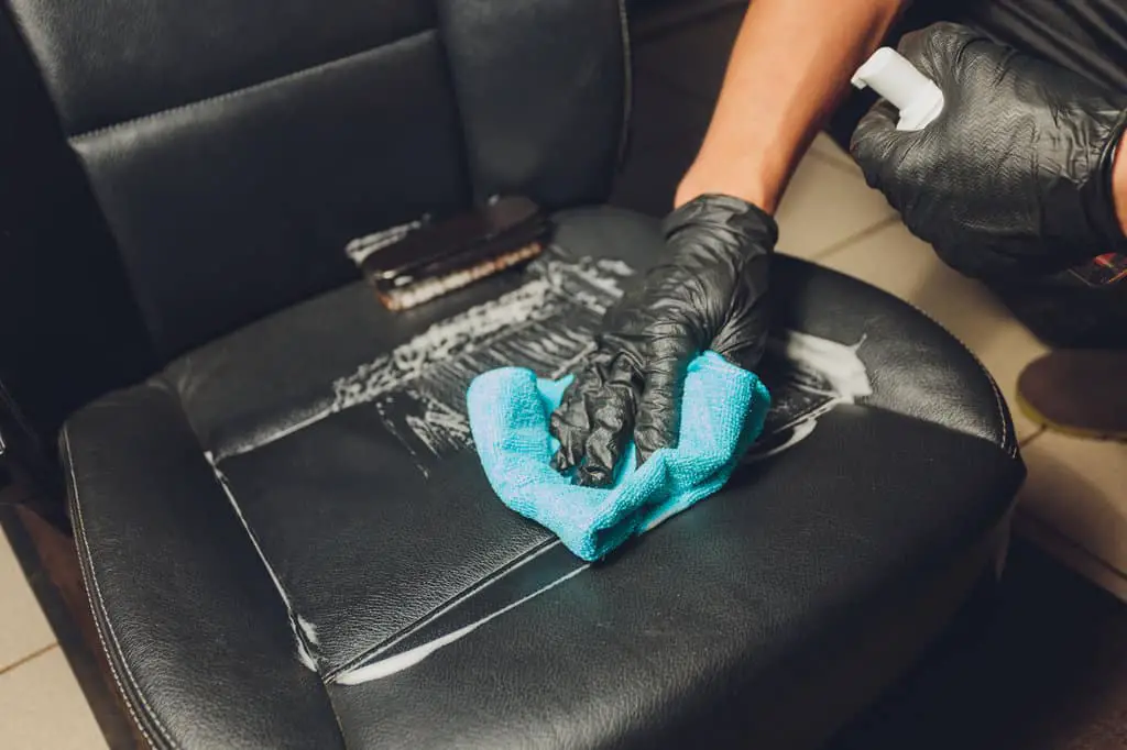 guy cleaning urine on black leather car seat