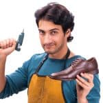 Young handsome shoemaker holding hot glue gun