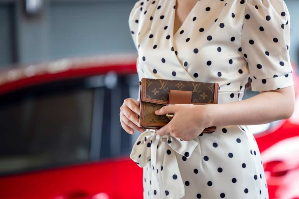 A woman carrying a Louis Vuitton square luxe leather bag.